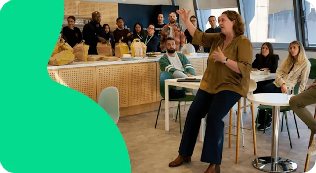 A photo of a company meeting being held in the office kitchen area