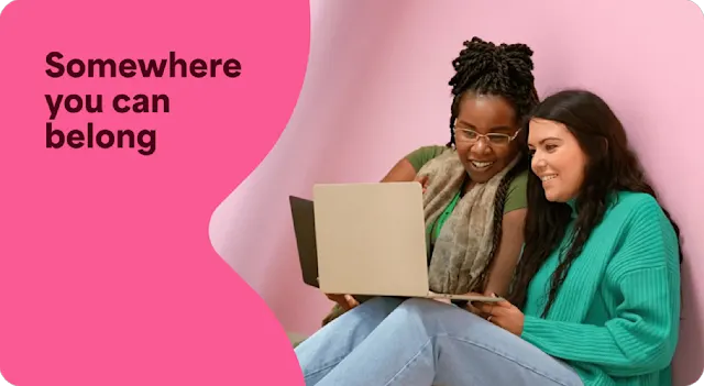 A photo of two employees working together on a laptop. There is a text overlay that says Somewhere you can belong